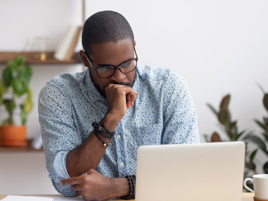man thinking at laptop screen
